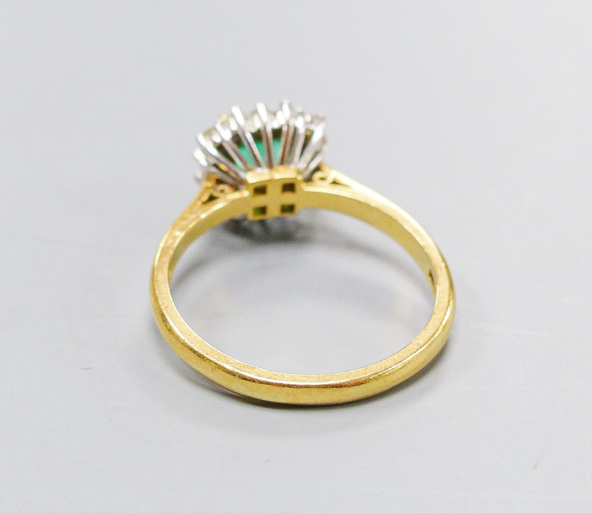 A modern 18ct gold, emerald and diamond set square cluster ring, size O, gross weight 4.3 grams.
